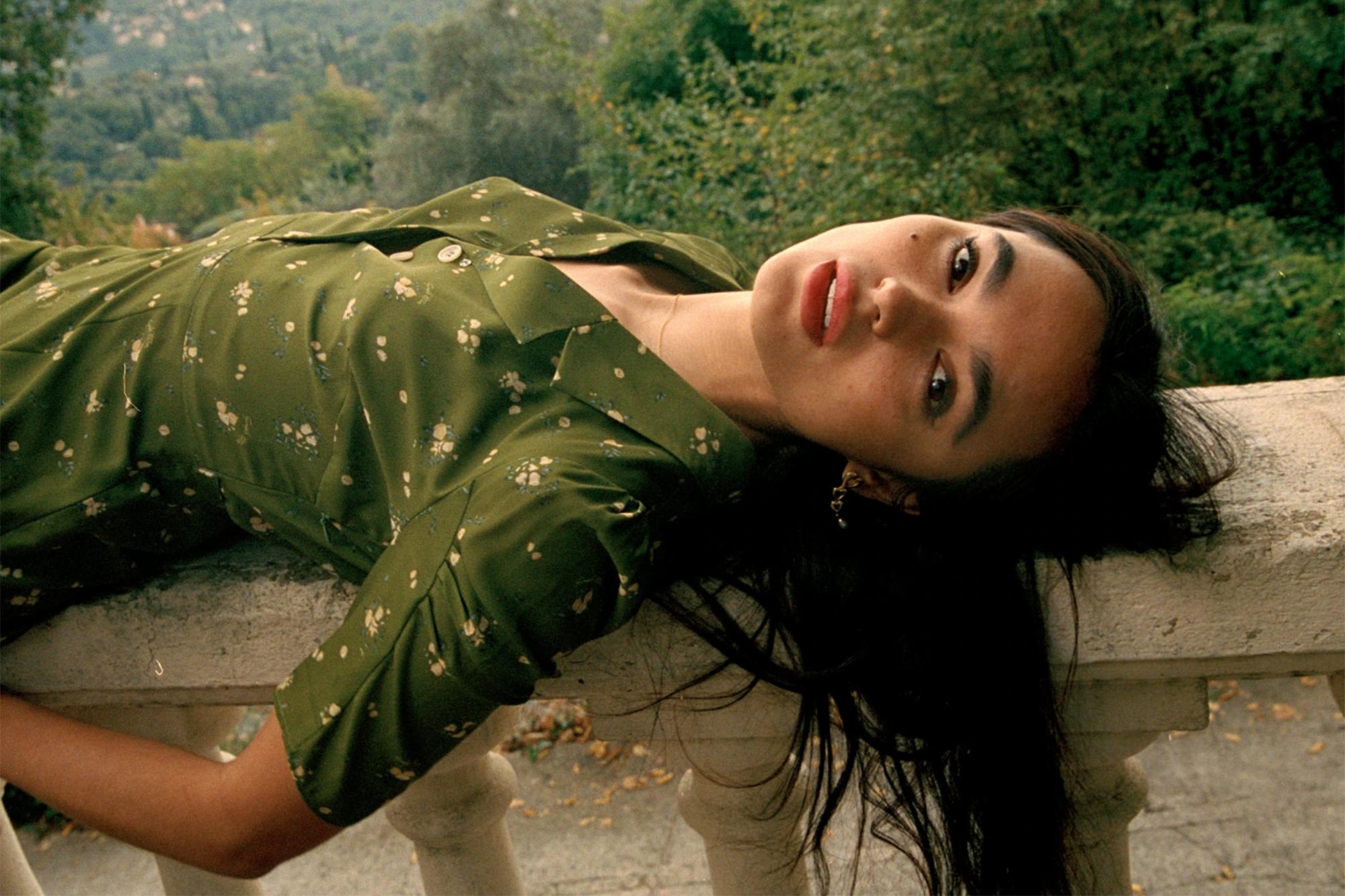 Woman laying on back wearing green dress