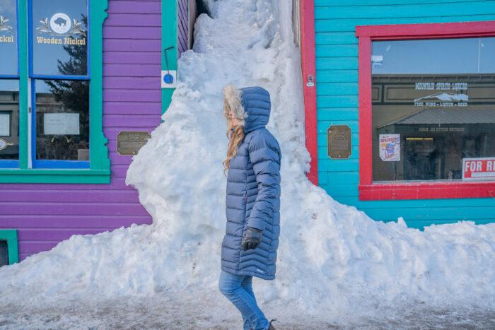 Woman wearing winter parka sitting on storefront bench