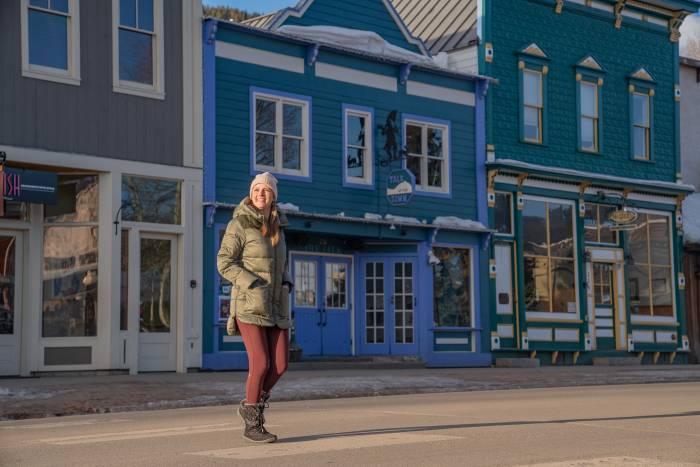 Two women wearing winter jackets and sitting in outdoor chairs at a storefront