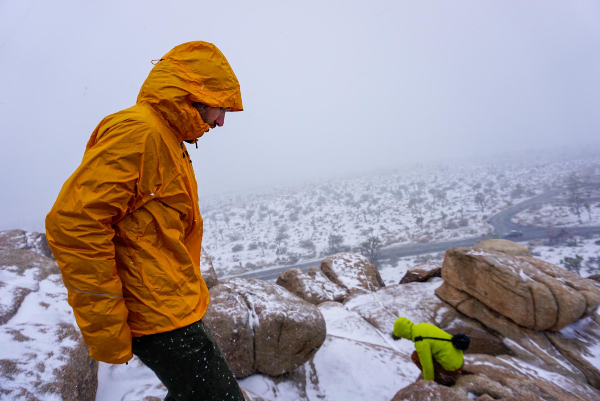 Hiker Wearing the Outdoor Research Helium Rain Jacket Descends Boulders in Joshua Tree National Park