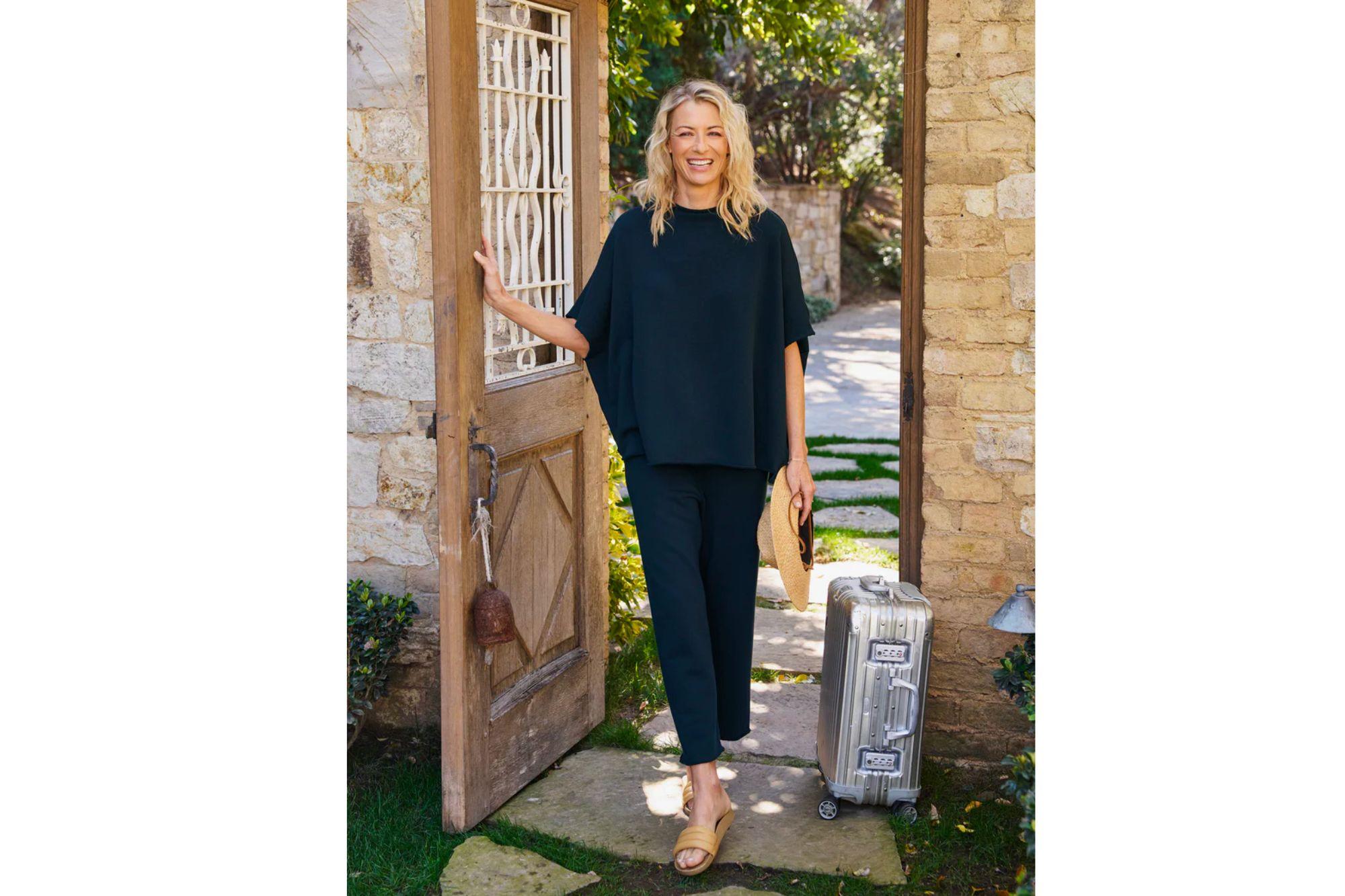 Woman outside with a suitcase, wearing a dark blue loungewear set.