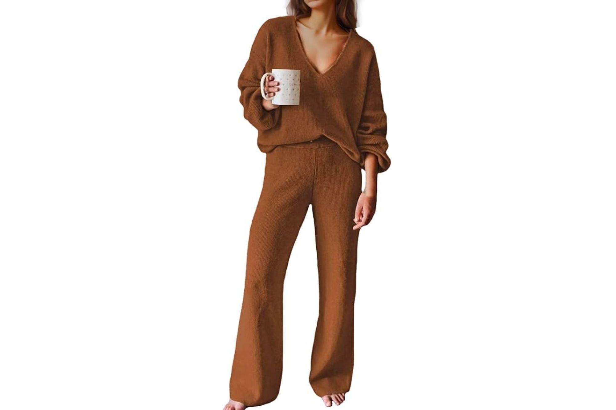 A woman holding a cup of coffee and wearing a dark brown loungewear outfit.