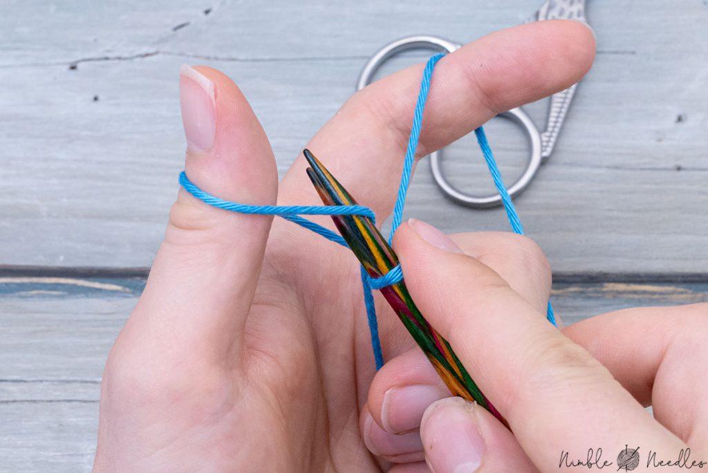 inserting both needles into the loop around the thumb