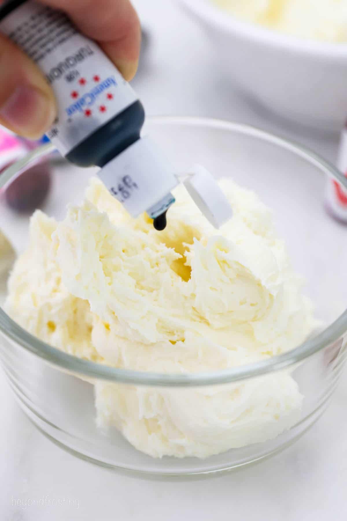 Light turquoise buttercream in a glass bowl with an offset spatula.