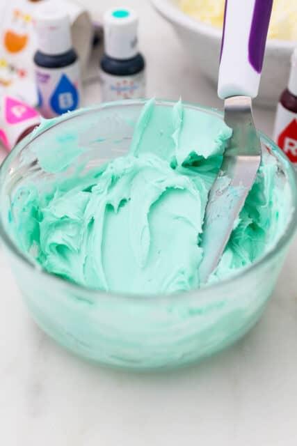 Pink food dye partially mixed into a bowl of vanilla buttercream frosting.