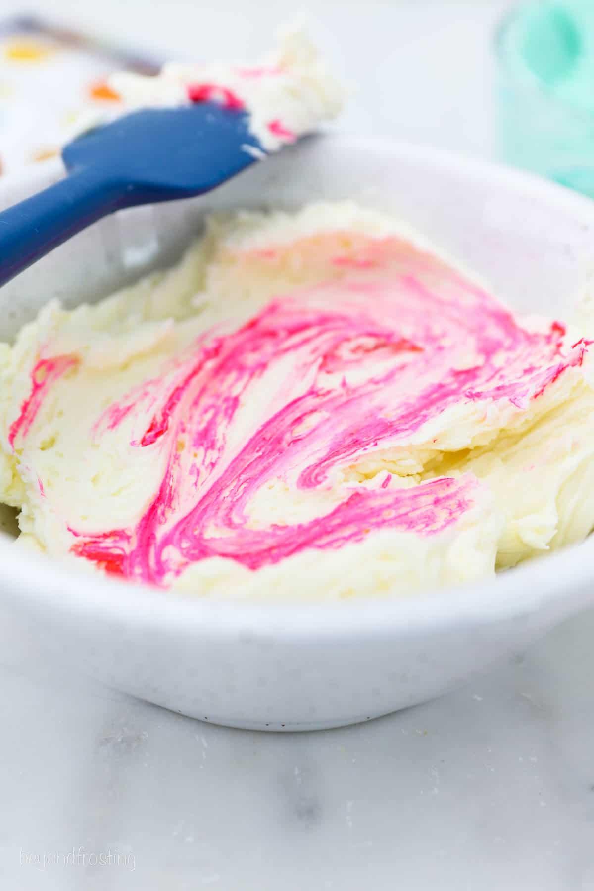 A piping bag with a tip filled with pink buttercream frosting.