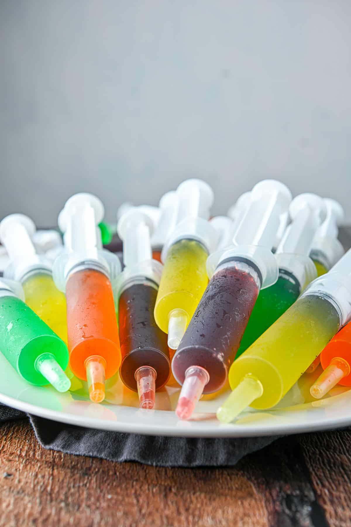 A beige plate piled with jello shot syringes