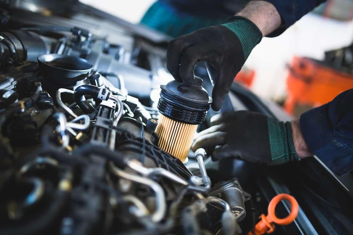 Close up hands of unrecognizable mechanic doing car service and maintenance. Oil and fuel filter changing., How To Reset Fuel Filter Life On A Duramax