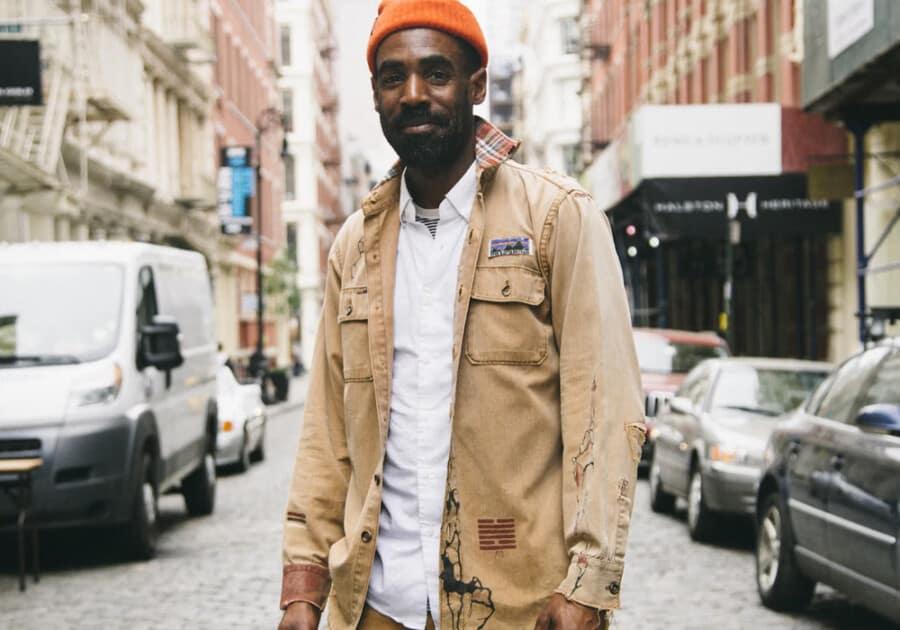 Man wearing a white shirt, khaki field jacket by Patagonia and orange beanie