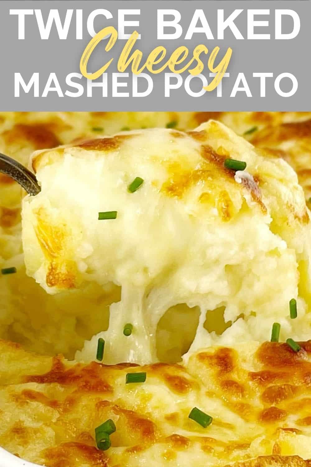 a spoon digging into baked mashed potato covered in melted cheese in a white casserole dish.