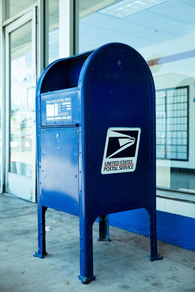 a united states postal service mailbox on a concrete slab.