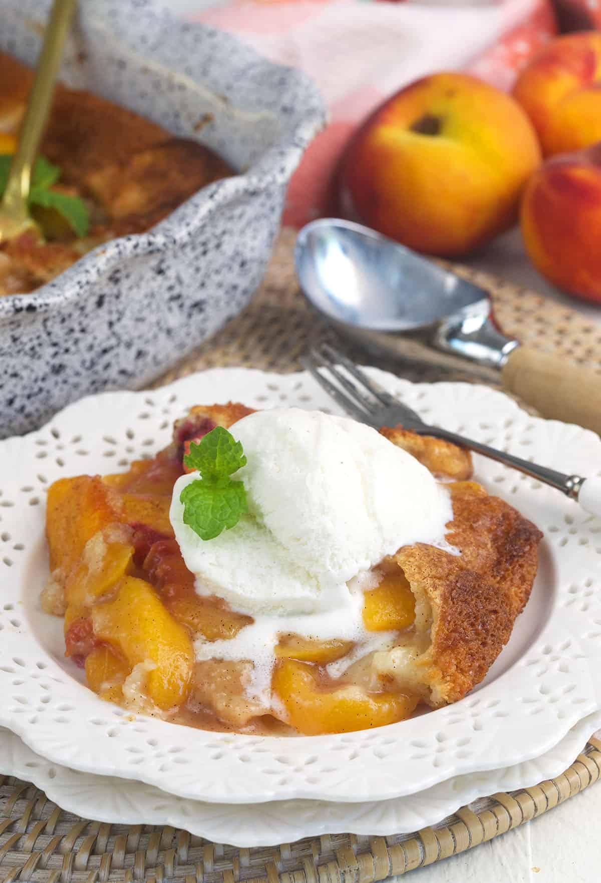 A scoop of vanilla ice cream is placed on top of a serving of peach cobbler.