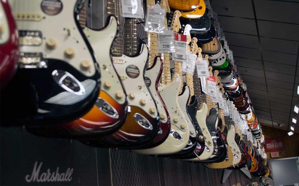 variety of electric guitars on the wall of a guitar store