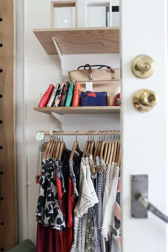 a rack of clothing items hanging on wooden hangers.