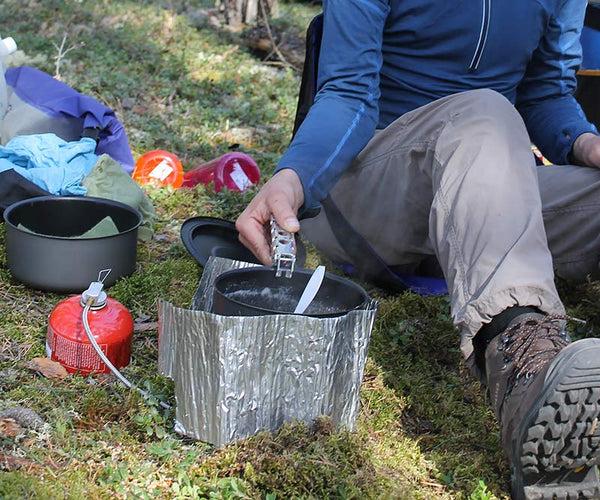 person cooking on a backpacking stove