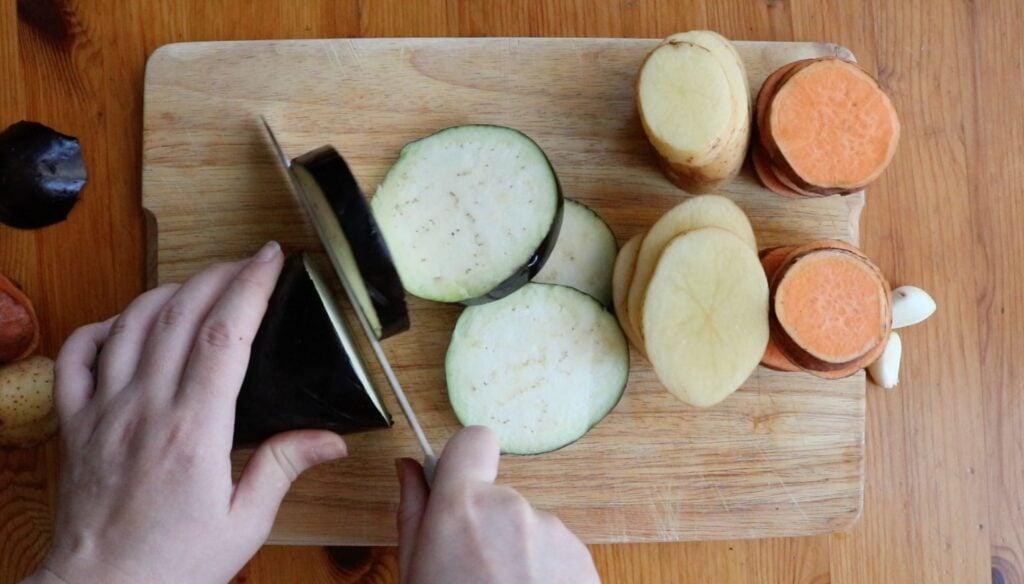 Sliced potatoes and eggplant on a baking tray with garlic.