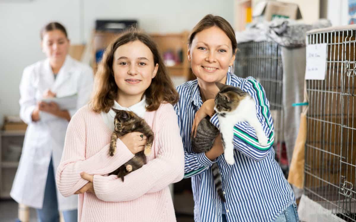 Happy preteen girl and her mother standing in shelter for abandoned animals