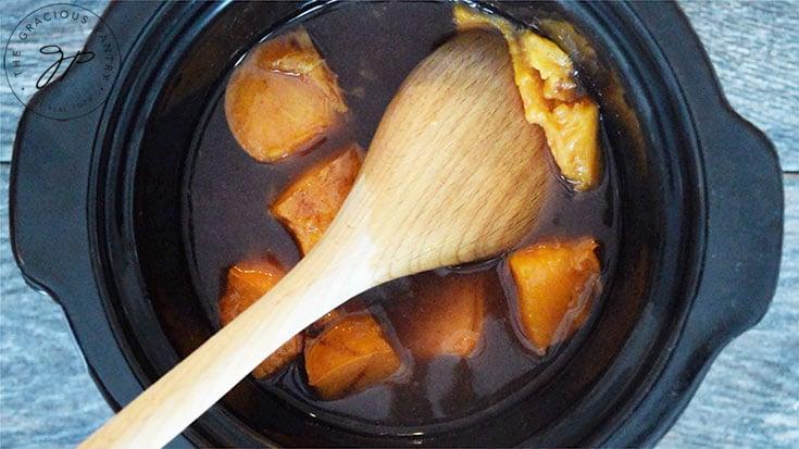 Squishing a persimmon against the side of the slow cooker to check it