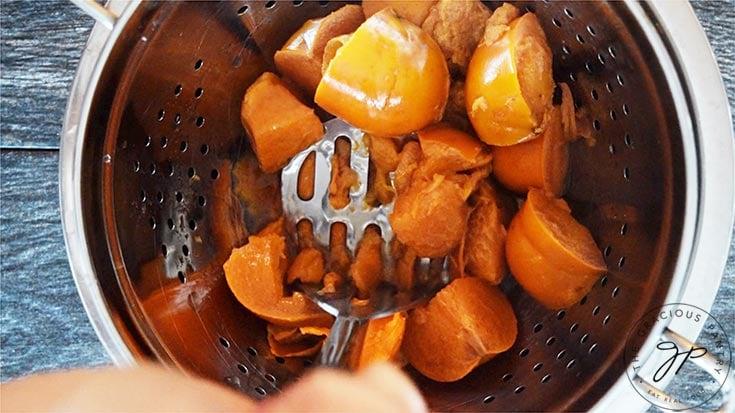 Mashing the persimmons with a potato masher to make the persimmon pulp.