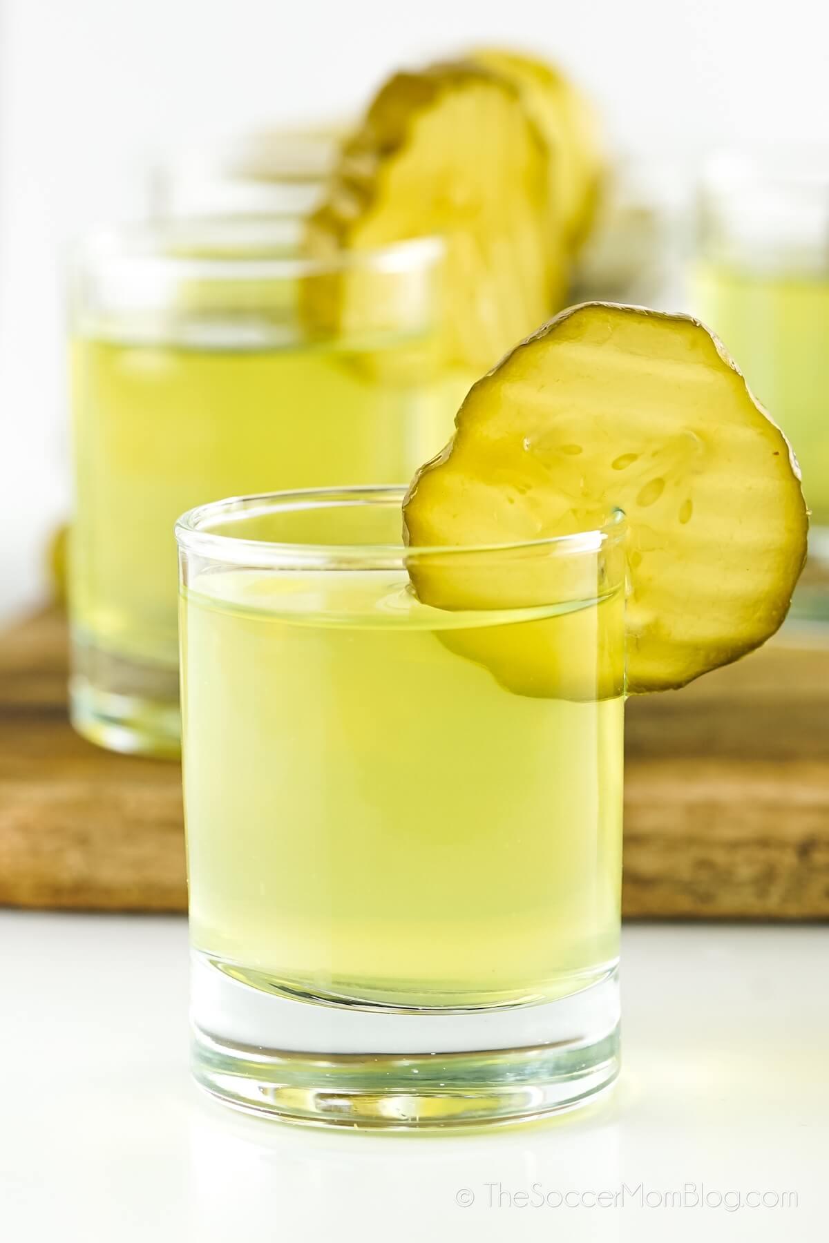 Dill Pickle Shots lined up on a table, with pickle chip garnish