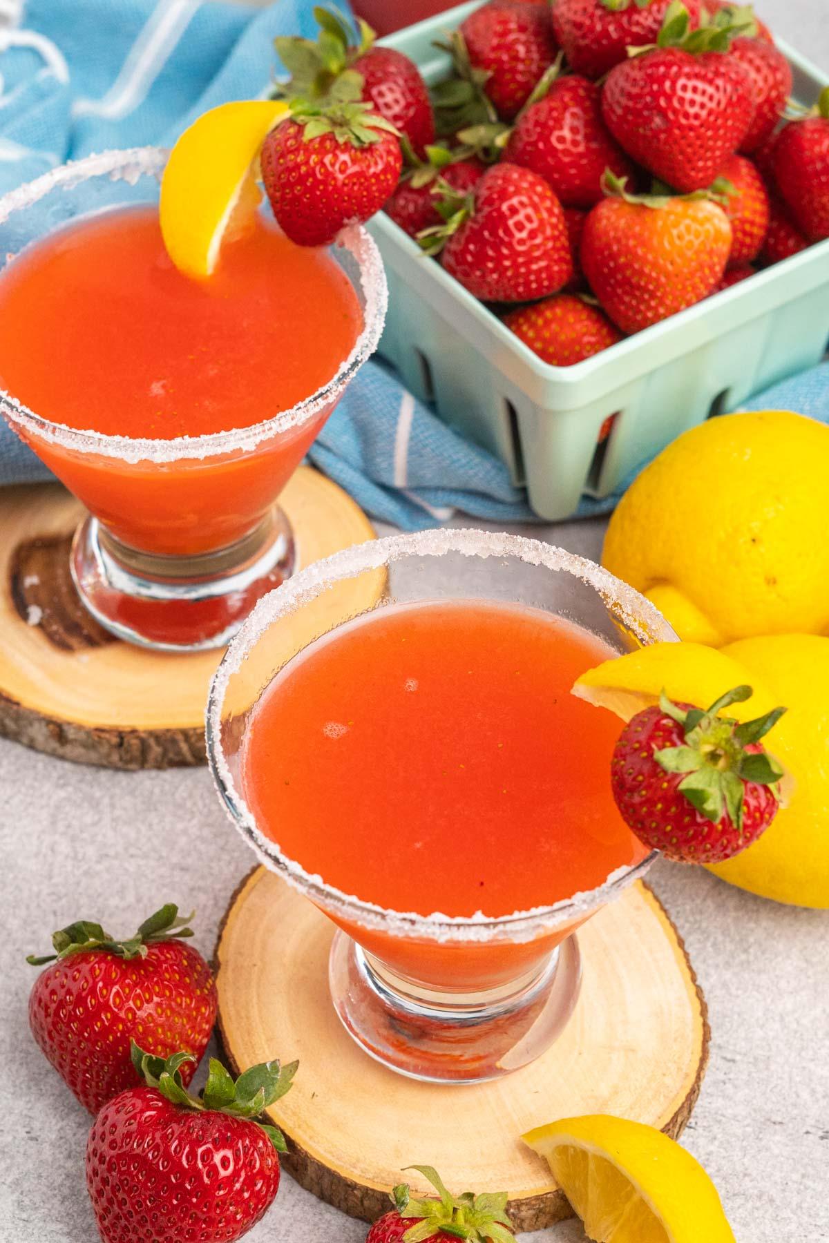 Top view of two strawberry lemon martinis garnished with sugared rim, a strawberry and lemon wedge.