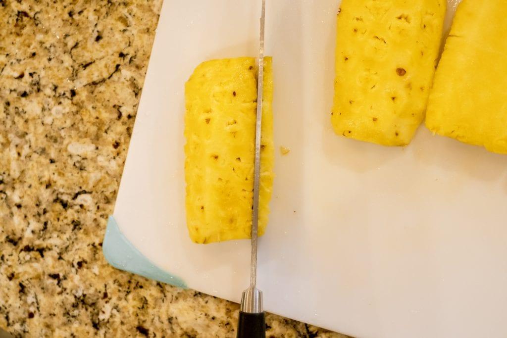 cutting pineapple quarter into thin slices