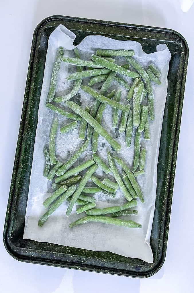 The frozen green beans now coated in olive oil and with the herbs and spices added.