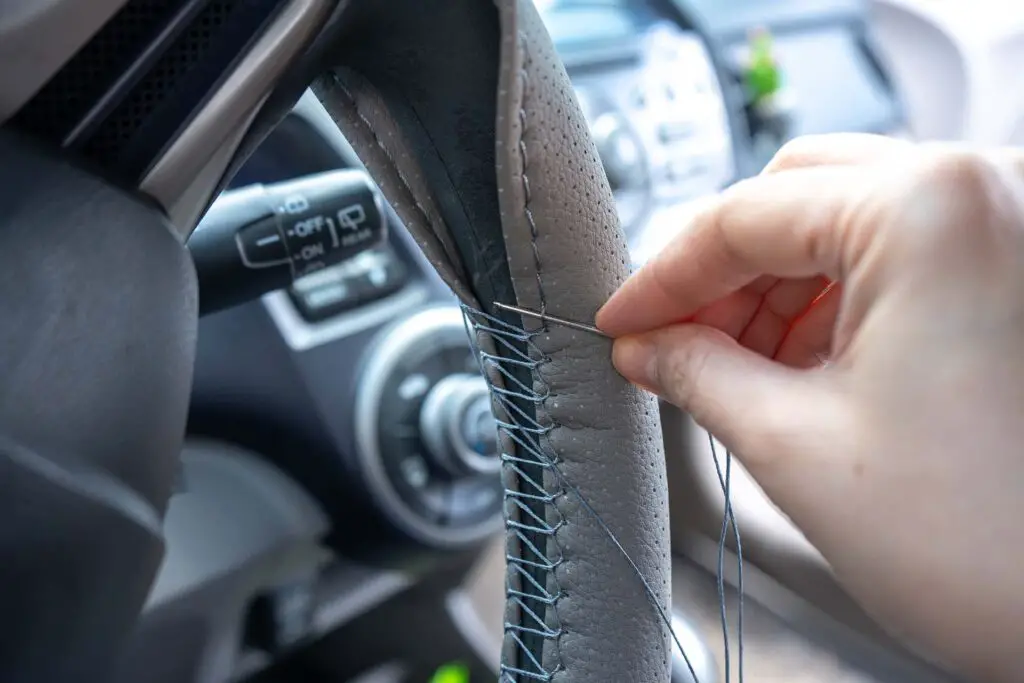 Braided steering wheel with leather cover. The mechanic change a new cover of the steering wheel of the car. Renewal of steering wheel cover.