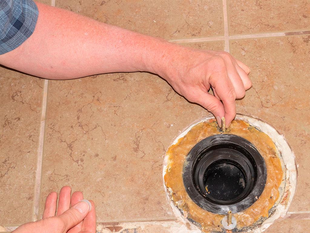 Man changing bolts on a toilet wax ring