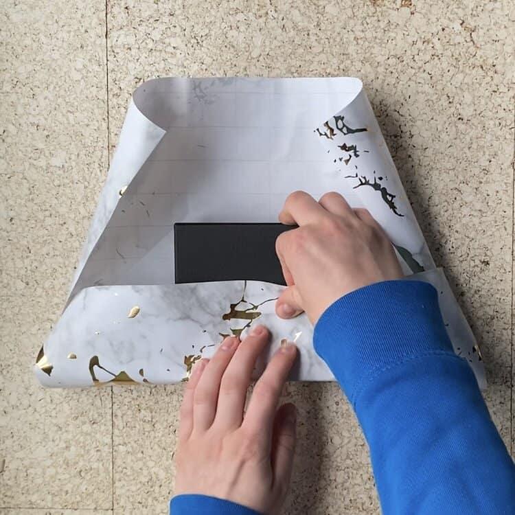 Wrapping a jewelry package in wrapping paper to put a card on the outside.