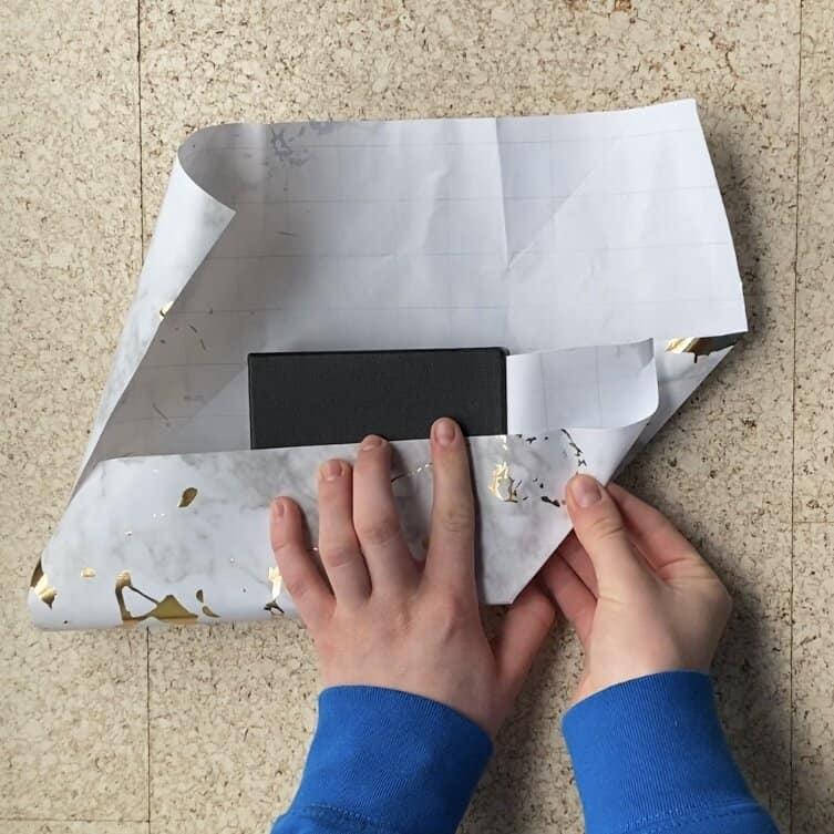 Wrapping a jewelry package in wrapping paper to put a card on the outside.