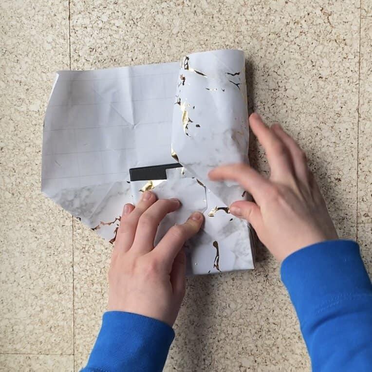 Wrapping a jewelry package in wrapping paper to put a card on the outside.